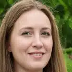 Gros plan d'une femme souriante entourée d'arbres Jeux Montessori.