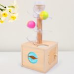 La Boite en Bois Toboggan Permanence d'Objets 3 Sorties contenant des balles colorées.