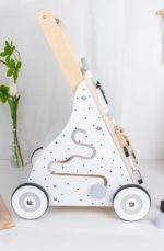 Un Trotteur pousseur bébé - multi-activités - Couleurs pastel est posé sur une table à côté d'un pot de fleur.