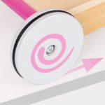 Un Trotteur Chariot de Marche Bébé rose - Petit Panier avec un rouet blanc sur une table en bois.