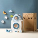 Une fusée jouet posée sur une table à côté d’une boîte.