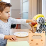 Un jeune garçon nourrit un jouet pour chat en bois.