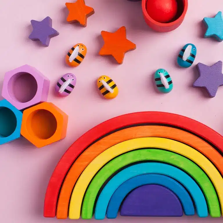 Jouets en bois colorés sur fond rose.