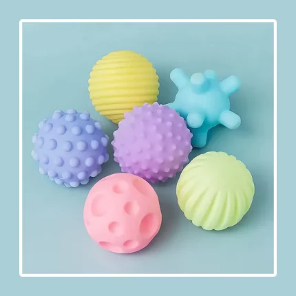 Set de 6 boules sensorielles pour bébés - Texturées disposées sur fond bleu clair.