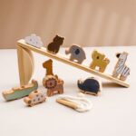 L'ensemble « Jouet montessori animaux en bois » comprend des jouets en bois comme des éléphants, des zèbres et des girafes disposés sur une rampe triangulaire en bois avec une corde blanche devant pour une scène Montessori classique.