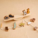 La collection Jouet Montessori animaux en bois présente des figurines d'animaux en bois (éléphant, zèbre, girafe, lion, ours et crocodile) en équilibre gracieux sur une balançoire et une ficelle dans un arrangement simple.