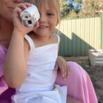 Une femme et un enfant sont assis dehors. L'enfant, un petit appareil photo à la main, rayonne d'excitation, comme s'il venait de découvrir un monde extraordinaire à travers l'objectif d'un microscope portatif.