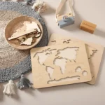 Le « Puzzle du monde en bois Montessori » repose sur un tapis à pompons texturé, avec un petit panier, un appareil photo jouet et des blocs de bois étiquetés « Halloween » et « Pâques », capturant l'essence tactile de l'apprentissage Montessori.