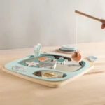 Le Puzzle pêche en bois magnétique présente des pièces magnifiquement travaillées sur une table, avec une main utilisant habilement la canne à pêche pour soulever une pièce et donner vie au puzzle.