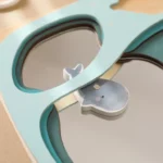 Un gros plan du Puzzle pêche en bois magnétique montre un puzzle à plusieurs niveaux avec des cadres en bois et une pièce de baleine partiellement retirée, découvrant un miroir. Cela ajoute de l'intrigue au design ludique.