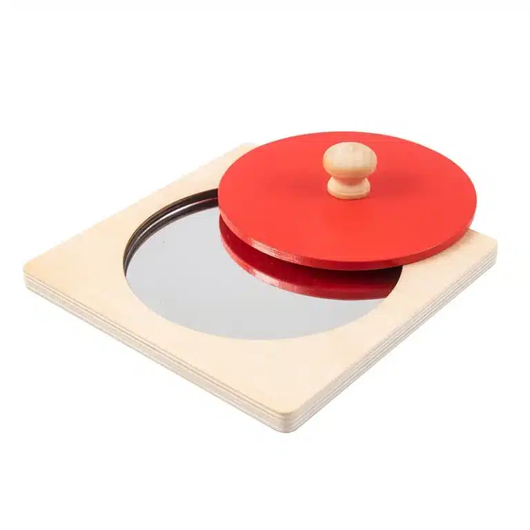 Le « Puzzle miroir en bois montessori » présente un plateau circulaire en bois rouge qui tourne sur une base carrée, révélant partiellement un miroir en dessous.