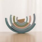 L'Arc en ciel Montessori en Silicone présente des demi-cercles pastel empilés sur une surface en bois avec un fond clair, évoquant une esthétique arc-en-ciel élégante et douce.